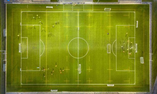Aerial view of soccer field while athletes are training at night under bright stadium lights